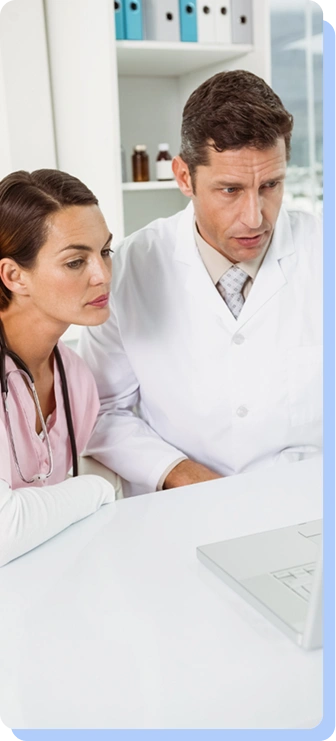 A male and female medical professional looking intently at a computer screen together, representing a collaborative review of medical information.