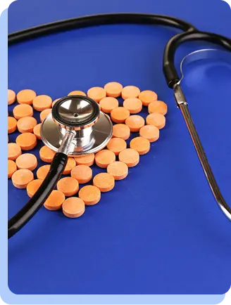 A close-up of a stethoscope lying on top of a heart shape made entirely of orange medicinal pills.