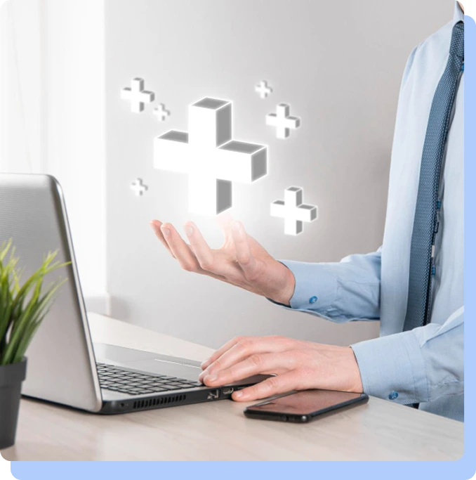 A person at a desk with a laptop and phone, with their hand outstretched beneath floating 3D medical cross icons, symbolizing digital healthcare and medical evaluation.
