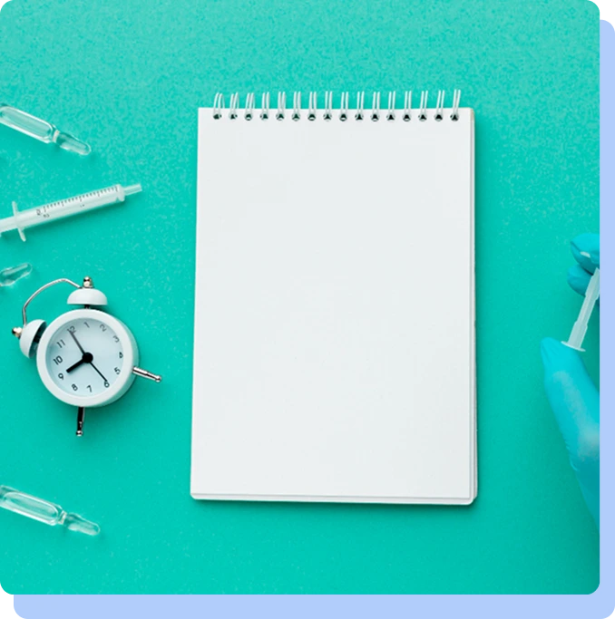 A top-down view of a blank notebook, a small white alarm clock, and syringes on a bright green background.