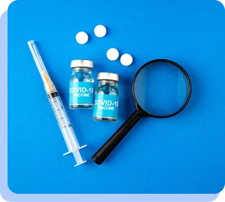 A syringe, two blue vials, a magnifying glass, and several white pills on a bright blue background.