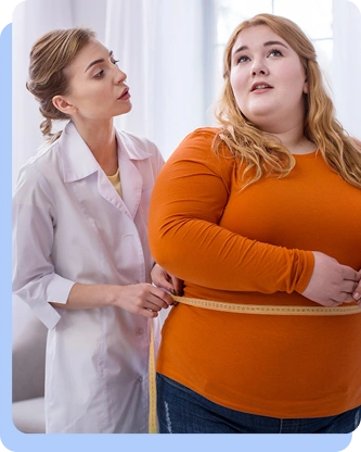 A female healthcare professional in a white coat uses a yellow measuring tape to measure the waist circumference of a female patient wearing an orange shirt.