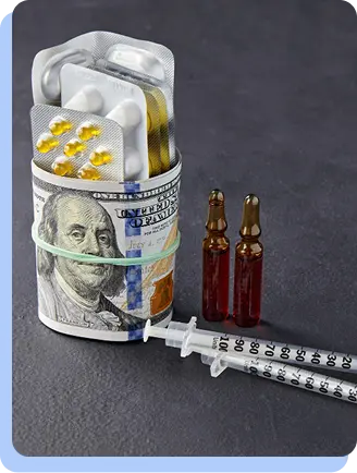 A roll of US hundred-dollar bills secured with a rubber band, holding blister packs of yellow pills and two brown glass vials next to a syringe.