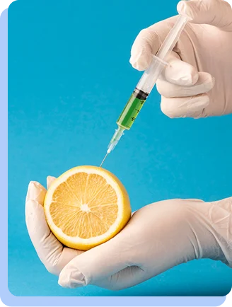 Gloved hands holding a syringe with green liquid over a sliced lemon.