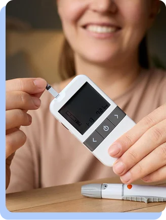A close-up of a smiling person's hands using a digital glucose meter to check their blood sugar levels.