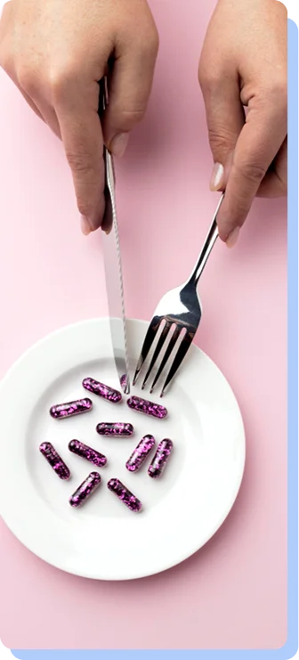 Close-up of a person using a silver knife and fork to "eat" small purple capsules from a white plate, representing the pharmacological approach to appetite control.