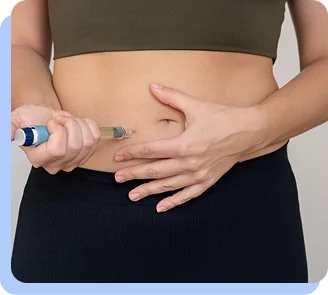 A close-up of a person's midsection as they hold a small fold of skin and prepare to administer an injection with a blue pen.