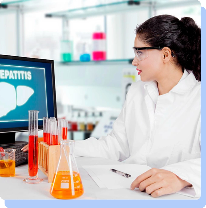A female scientist with glasses and a white lab coat works at a desk in a laboratory. She is looking at a computer monitor displaying a liver icon and the word "HEPATITIS." On her desk are several beakers and test tubes filled with orange and red liquids.