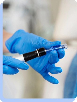 Gloved hands carefully adjusting a medical injection pen, showing the preparation phase of treatment.