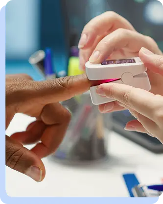 A healthcare professional placing a pulse oximeter on a patient's finger to monitor oxygen levels and metabolic health.